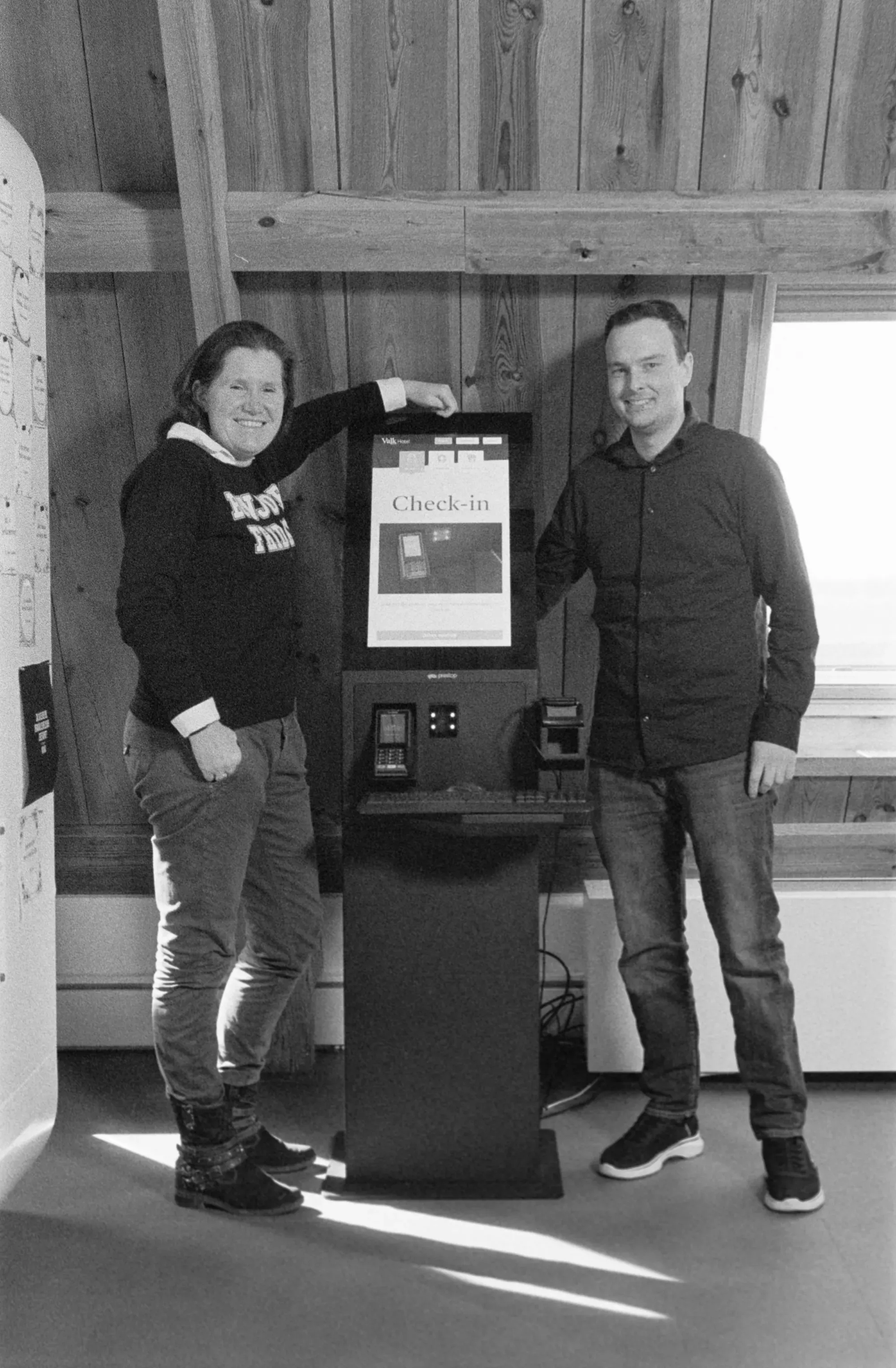 Two colleagues are standing at a check-in kiosk